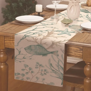 Détail d'un chemin de table en lin avec motifs de poissons et coraux sur une table en bois