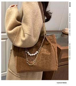 Dettaglio borsa tote leopardata con catena dorata e ciondolo con perla fine