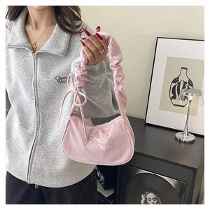 Dettaglio della borsa sottobraccio in velluto rosa con fiocco bianco e tracolla arricciata