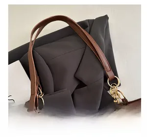 Dettaglio borsa tote in pelle marrone con anelli dorati ed elegante ciondolo di perle