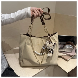 Dettaglio borsa tote bianco sporco con catena dorata, perla e ciondolo di leopardo