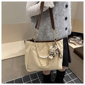 Dettaglio di una borsa tote grande con catena di perle e ciondolo gatto leopardato