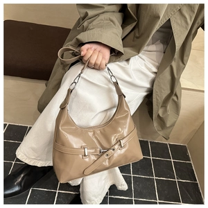 Detail of light brown patent leather hobo bag with decorative buckle and metal chain strap