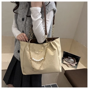 Dettaglio borsa tote leopardata beige con catena dorata e perle in un ambiente ufficio