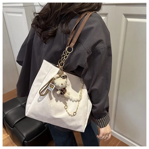 Dettaglio della borsa tote bianca con tracolla in pelle, catena di perle e ciondolo