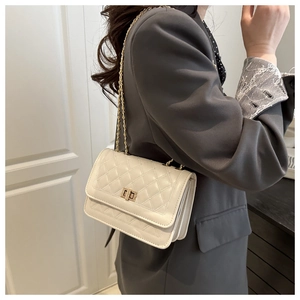 Détail du sac bandoulière crème avec fermoir rotatif doré et bandoulière chaîne