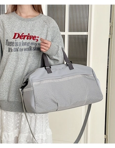 Dettaglio borsa da viaggio grigia con cuciture in mesh, doppi manici e tracolla rimovibile