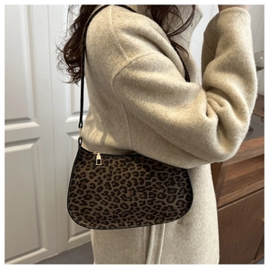 Chic leopard print hobo bag with black shoulder strap worn over a wool coat for daily wear