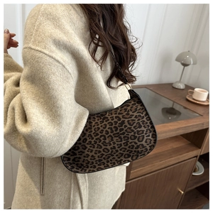 Chic leopard print half-moon underarm bag styled with a beige coat in a cozy home setting
