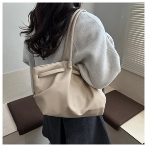 Vue détaillée du sac cabas plissé beige montrant la texture cuir sur l'épaule