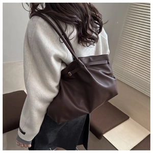 Détail du sac cabas plissé marron foncé avec texture litchi porté par un mannequin
