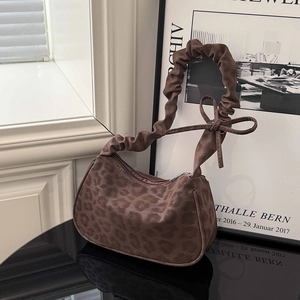 Borsa hobo leopardata con manico arricciato e fiocco su un davanzale di casa