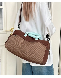 Borsa da viaggio marrone con motivo a quadri indossata da modella in stanza sobria