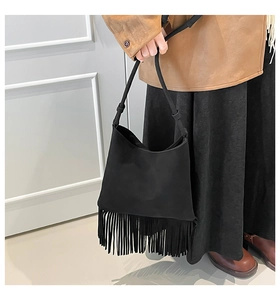 Gros plan sur le sac à bandoulière minimaliste noir en daim avec de longues franges