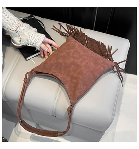 Détail d'un sac à bandoulière marron vintage avec de longues franges et une texture mate