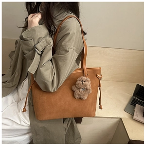 Détail d'un grand sac cabas marron mat avec breloque ours en peluche et cordon de serrage latéral