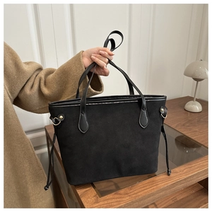 Close-up of black tote bag featuring matte suede texture and gold hardware details