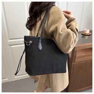 Detail of black matte tote bag with side drawstring and gold ring on a female model