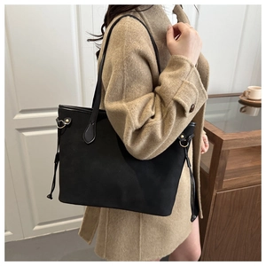 Close-up of matte black leather tote bag featuring drawstring tassels on a model shoulder