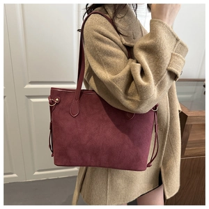 Close-up of a burgundy suede tote bag featuring elegant drawstring and gold hardware details