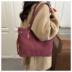 Detail of burgundy suede tote bag with metal ring and drawstring side accents