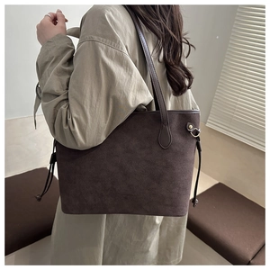 Detailed view of deep brown faux suede tote bag on model wearing a beige trench coat