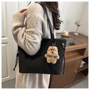 Detail of black large tote bag featuring side drawstrings and plush dog accessory