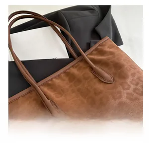 Macro detail of the leopard print texture and gold logo on a brown suede tote bag