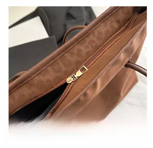 Detail of a smooth metal zipper on a large dark brown tote bag with matte texture
