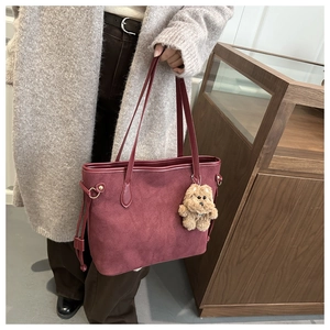 Détail du grand sac cabas bordeaux avec texture dépolie et pendentif ours en peluche marron