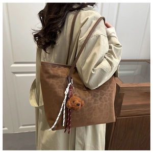 Close-up of leopard print tote bag featuring a cute brown teddy bear keychain and strap charm