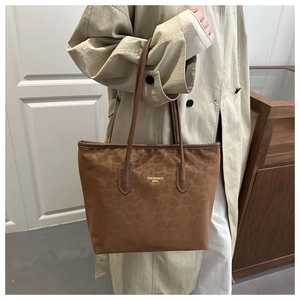 Brown leopard print tote bag with gold logo on beige trench coat for autumn style