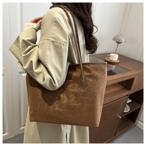 Brown leopard print tote bag with leather straps worn by model in beige trench coat