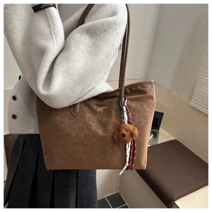 Détail du sac cabas léopard avec breloque chiot marron et logo de marque doré sur nylon
