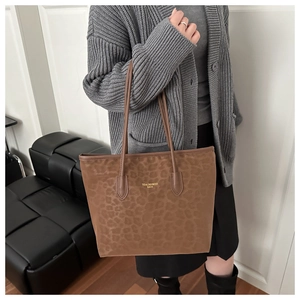 Detailed close-up of brown leopard print tote bag featuring gold text and suede texture