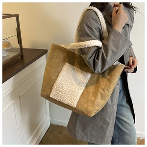 Dettaglio di una borsa tote in camoscio marrone con tasca in peluche bianca e tracolla soffice