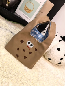 Detail of cute brown canvas tote bag with cartoon cookie embroidery and blue plaid lining