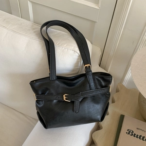Borsa a spalla retrò nera in ecopelle testurizzata con fibbie dorate su divano bianco