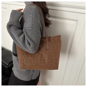 Detail of leopard print tote bag featuring gold lettering and leather shoulder strap