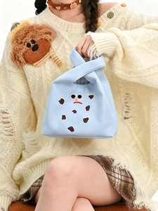 Close-up of light blue handbag with cute monster embroidery and checkered lining