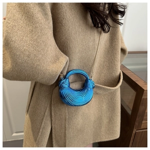 Dettaglio borsa a mano blu elettrico in acrilico con texture a pieghe e catena d'oro