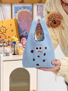 Dettaglio borsa in tela azzurra con ricamo a fumetti e fodera interna a quadri