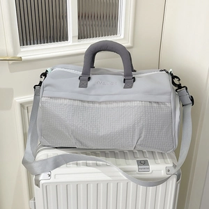 Borsa da viaggio grigia capiente con trama a quadretti sopra una valigia