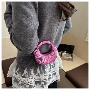 Dettaglio borsa a conchiglia in acrilico rosa con trama a righe e tracolla dorata