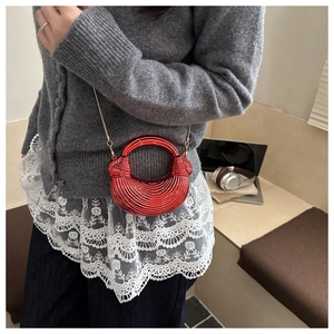 Dettaglio della pochette da sera rossa metallizzata con trama ondulata e catena oro