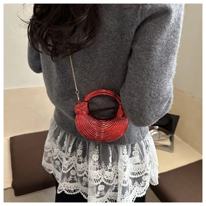 Detail of red metallic striped acrylic shell bag with golden chain on shoulder