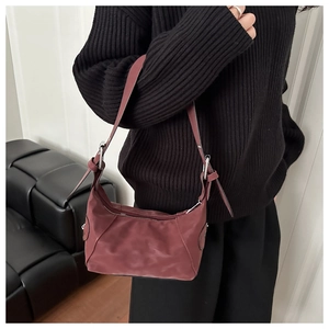 Detail of burgundy nylon crescent bag with silver metal ring and adjustable strap