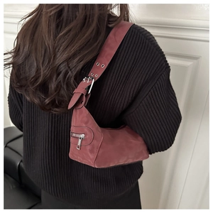 Detail of burgundy crescent shoulder bag with silver eyelet strap on model