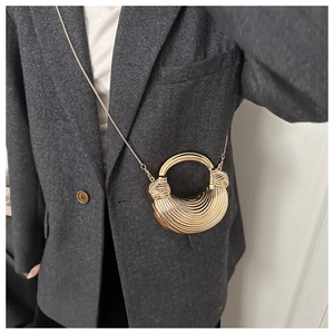 Dettaglio della borsa da sera a conchiglia dorata con strisce testurizzate e catena sottile