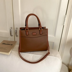 Grande borsa tote marrone caramello in ecopelle su divano bianco con finiture dorate